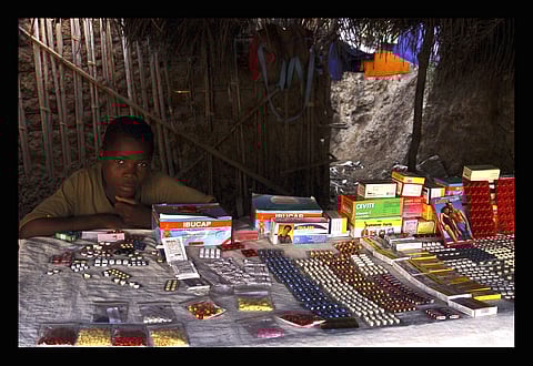 A person sitting behind a table with drugs and medication laid out.