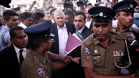 Ranil Wickremesinghe surrounded by police and lawyers coming out of the courtroom after being arrested for misusing state funds.
