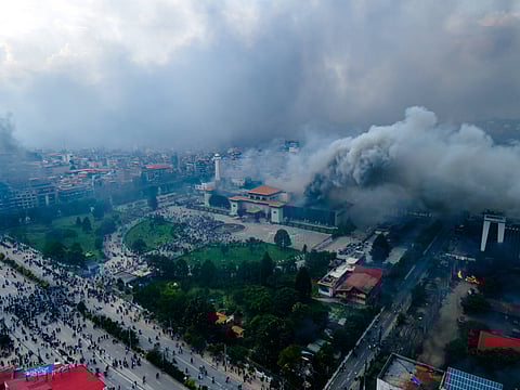Drone view of Nepal's parliament building on fire, with anti-corruption Gen Z protests on the streets before the complex.