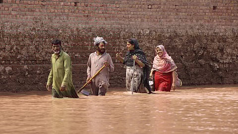 People wade through water in Pakistan’s Punjab province. By mid-September, at least 900 people had died and about four million were impacted by the floods that ravaged the country during the monsoon months.