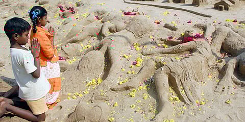 Children praying in front of sand sculptures