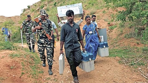 வாணியம்பாடி அடுத்த நெக்னாமலையில் அமைக்கப்பட்டுள்ள வாக்குச்சாவடிக்கு துணை ராணுவ வீரர்கள் பாதுகாப்புடன் வாக்குப்பதிவு இயந்திரங்களை சுமந்து செல்லும் தேர்தல் அலுவலர்கள்.படம்: விஎம்.மணிநாதன்