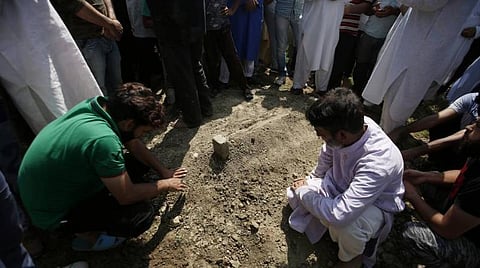 இறந்த அஸ்ரர் அகமெட் புதைக்கப்பட்ட இடத்தில் உறவினர்கள். | ராய்ட்டர்ஸ்.