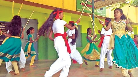 ஆசிரியையின் இசைக்கேற்ப சாட்டைக் குச்சி ஆட்டமாடும் மாணவர்கள்.