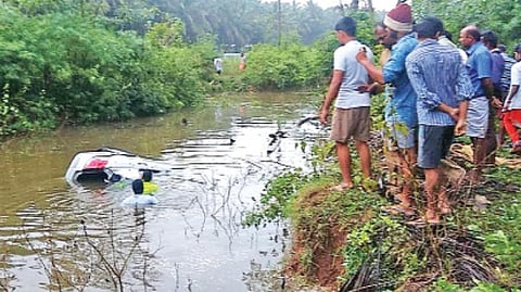 பொள்ளாச்சி அருகே பள்ளத்தில் தேங்கிய தண்ணீரில் கவிழ்ந்து விபத்துக்குள்ளான காரை மீட்கும் தீயணைப்பு துறையினர்.