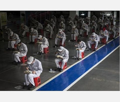 சீனாவின் ஹூபேயில் டாங்பெங் ஃபெங்ஷன் தொழிற்சாலையில் ஊழியர்கள் 2 மீட்டர் இடைவெளி விட்டு அமர்ந்து உணவு உண்கிறார்கள். | கெட்டி இமேஜஸ்.