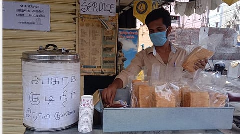 கோவை ரத்தினபுரி 7-வது வீதி தொடர்ச்சியில் உள்ள பேக்கரி முன்பு செயல்படும் ஆளில்லா ரொட்டிக்கடையில் ரொட்டி எடுத்துக் கொண்டு அதற்கான தொகையை அருகில் உள்ள பெட்டியில் போடும் இளைஞர். | படம்: த.சத்தியசீலன்.