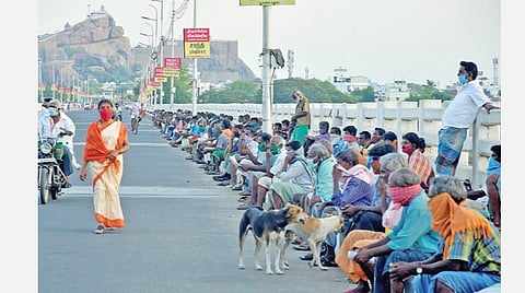 உணவு பெறுவதற்காக ஸ்ரீரங்கம் காவிரிப் பாலத்தில் காத்திருக்கும் தொழிலாளர்கள்.