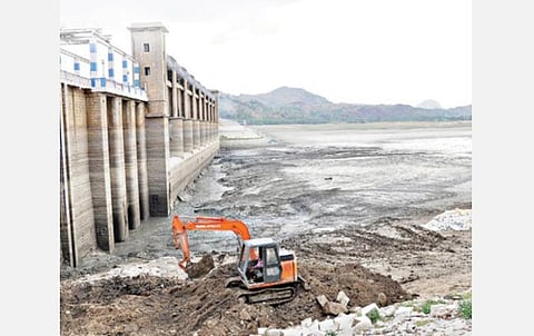 கிருஷ்ணகிரி அணையில் தேங்கியுள்ள சேற்றை பொக்லைன் மூலம் அகற்றும் பொதுப்பணித்துறையினர்.
