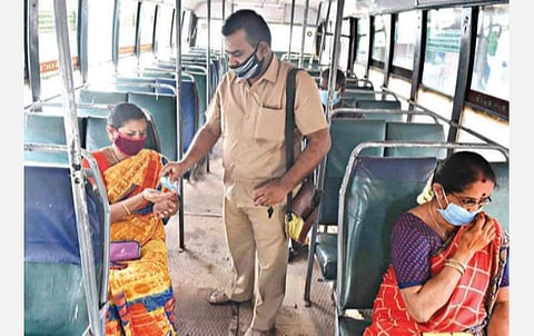 கோவையில் நேற்று குறைவான பயணிகளுடன் இயக்கப்பட்ட அரசுப் பேருந்தில் பயணிகளுக்கு சானிடைசர் வழங்கும் நடத்துநர். படம்: ஜெ.மனோகரன்.