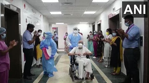 முதியவரை வழியனுப்பி வைக்கும் பணியாளர்கள்