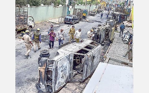 தீ வைத்து எரிக்கப்பட்ட வாகனங்களை போலீஸார் பார்வையிட்டு ஆய்வு செய்கின்றனர்.