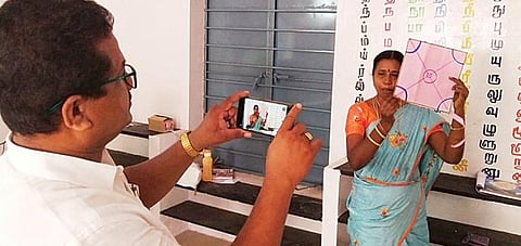 அம்மையநாயக்கனூர் அரசு தொடக்கப் பள்ளியில் ஆசிரியர் பாடம் நடத்த அதை செல்போனில் வீடியோ எடுக்கும் மற்றொரு ஆசிரியர்.