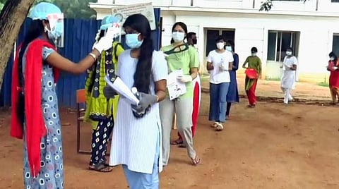 நீட் தேர்வெழுத வந்த மாணவிக்கு வெப்பநிலை பரிசோதிக்கப்படுகிறது.