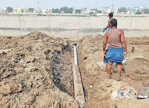 கழிவுநீரை வெளியேற்ற மதுரை சந்தைப்பேட்டை அருகே வைகை ஆற்றின் கரையோரத்தில் கட்டிய தடுப்புச் சுவரில் துளையிட்டு குழாய் அமைக்கும் பணியாளர்கள்.