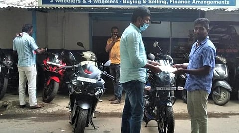 கோவையில் உள்ள ஒரு பழைய இருசக்கர வாகன விற்பனையகத்தில் விற்பனையாளரிமிருந்து வாகனத்தைப் பெற்றுக்கொள்ளும் வாடிக்கையாளர்.