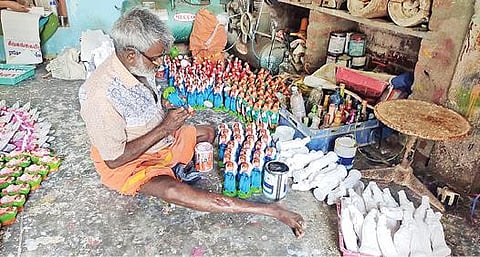 கிறிஸ்துமஸ் பொம்மை தயாரிப்பில் ஈடுபட்டுள்ள முதியவர்.