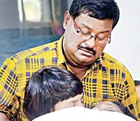 தாயின் உடலைப் பார்த்து அழும் குழந்தையை சமாதானம் செய்யும் தந்தை ஜாய்.