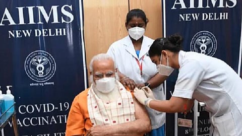 பிரதமர் மோடி தடுப்பூசி செலுத்துகிறார் செவிலி நிஷா சர்மா, பிரதமரின் கையை தாங்கிப் பிடித்துள்ளார் செவிலி நிவேதா.