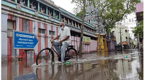 கொசப்பேட்டை விநாயகம் தெருவில் தேங்கிய தண்ணீரில் சைக்கிளில் செல்லும் முதியவர்.