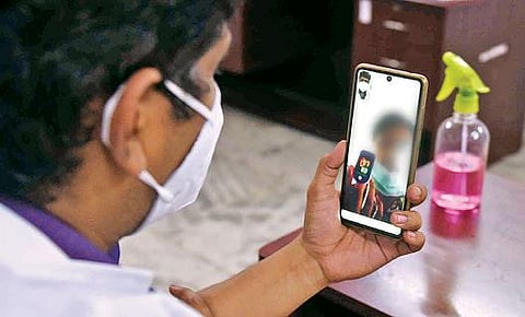 காந்திபுரத்தில் உள்ள நகர் நல மையத்திலிருந்து வீட்டில் தனிமைப்படுத்தப்பட்டுள்ள வரிடம் பேசும் சுகாதாரப் பிரிவு மருத்துவர். படம்: ஜெ.மனோகரன்