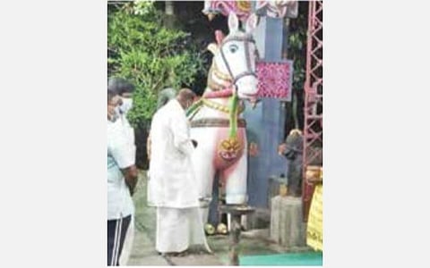 குதிரை சிலையின் கால்களில் வேண்டுதல் சீட்டு கட்டும் முதல்வர் ரங்கசாமி.