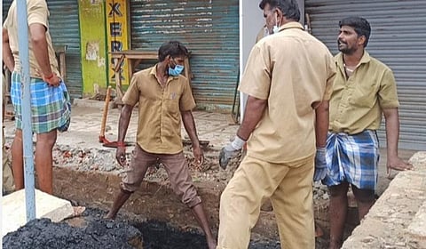 சிவகங்கை அரண்மனைவாசலில் பாதுகாப்பு கவசமின்றி கழிவுநீர் அடைப்பை சரிசெய்யும் நகராட்சி ஊழியர்கள்.