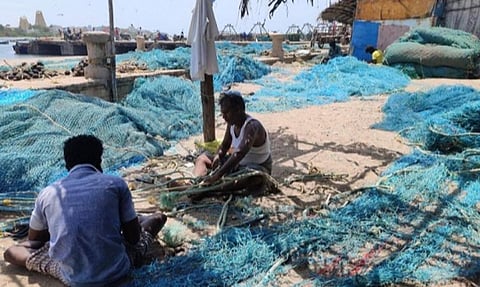 ராமேசுவரத்தில் வலைகளை சரி செய்யும் மீனவர்கள்.