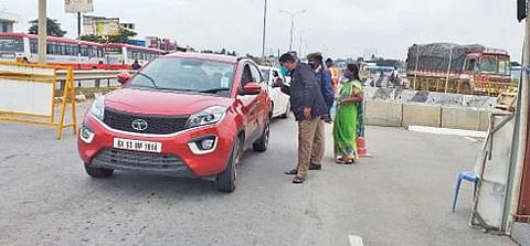 ஓசூர் ஜுஜுவாடி கரோனா சோதனைச்சாவடி மையத்தில் இ-பாஸ் வாகனச் சோதனையில் ஈடுபட்டுள்ள போலீஸார். உடன் கிருமி நாசினி தெளிப்பு பணியில் ஈடுபட்டுள்ள மாநகராட்சி பணியாளர்கள். படம்: ஜோதி ரவிசுகுமார்