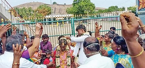 திண்டுக்கல் கோட்டை மாரியம்மன் கோயில் வாயில் முன் உறவினர்கள் சூழ மணமகள் கழுத்தில் தாலி கட்டிய மணமகன்.