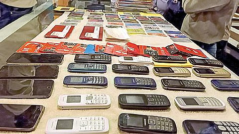 டெல்லியில் கைது செய்யப்பட்ட 3 பேருடன் தனிப்படை போலீஸார். (அடுத்த படம்) முறைகேடு செய்தோரிடம் பறிமுதல் செய்யப்பட்ட 31 செல்போன்கள்.