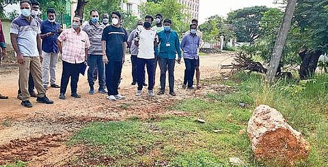 புவியியல் மற்றும் சுரங்கத் துறையின் மண்டல இணை இயக்குநர் அலுவலகத்தின் சுற்று சுவரோரம் வீசப்பட்டுள்ள கல்மரத் துண்டை ஆட்சியர் மோகன் பார்வை யிடுகிறார்.