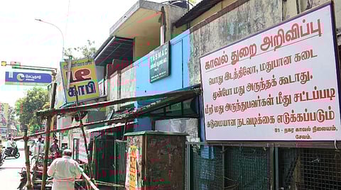 டாஸ்மாக் கடை முன்பு காவல்துறை சார்பில் வைக்கப்பட்டுள்ள அறிவிப்புப் பலகை. | படம்: எஸ்.குரு பிரசாத்.