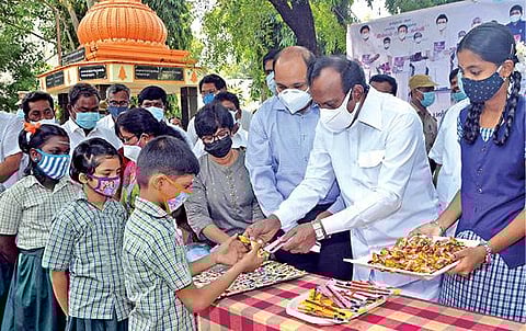 ஈரோடு அரசு மகளிர் மேல்நிலைப் பள்ளிக்கு வந்த மாணவியருக்கு, வீட்டுவசதித்துறை அமைச்சர் சு.முத்துசாமி இனிப்பு வழங்கி வரவேற்றார். அருகில் மாவட்ட ஆட்சியர் எச்.கிருஷ்ணன் உண்ணி.