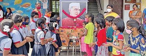 சின்னாளபட்டி சேரன் வித்யாலயாவில் நடந்த குழந்தைகள் தின விழாவில் முன்னாள் பிரதமர் நேரு உருவப்படத்துக்கு மலர் தூவி மரியாதை செய்த பள்ளி மாணவ, மாணவிகள்.