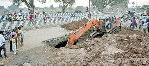 வேலூர் கோட்டை அகழியில் இருந்து உபரிநீர் வெளியேறும் கால்வாயில் அடைப்பை கண்டறிய மீன் மார்க்கெட் அருகே சாலையில் பொக்லைன் இயந்திரம் மூலம் தோண்டப்பட்ட பள்ளம். படம்: வி.எம்.மணிநாதன்.