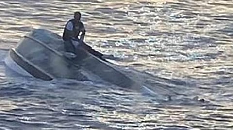 நடுக்கடல் விபத்தில் தப்பி, கவிழ்ந்த படகில் தத்தளித்த இளைஞர் - உலகை உலுக்கும் புகைப்பட பின்புலம்