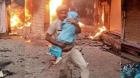 போர்வையில் குழந்தையைச் சுற்றி அணைத்தபடி மீட்டு வரும் கான்ஸ்டபிள் நேத்ரேஷ் சர்மா.