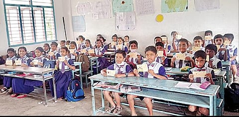 அஞ்சல் அட்டையில் பெற்றோருக்கு எழுதிய கடிதத்தை காண்பிக்கும் மாணவர்கள்.