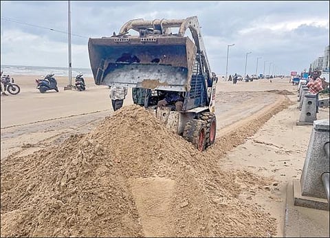 ‘மேன்டூஸ்’ புயல் காரணமாக கடல் அலைகளின் சீற்றத்தால், சென்னை பட்டினப்பாக்கம் கடற்கரை சாலையில் குவிந்த மணலை இயந்திரம் மூலம் அகற்றும் பணி நடைபெற்று வருகிறது.படம்: பு.க.பிரவீன்