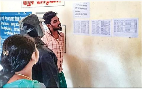 தஞ்சாவூர் அருகே உள்ள ரேஷன் கடை முன் ஒட்டப்பட்டுள்ள, வங்கிக் கணக்கு விவரம் இல்லாத ரேஷன்கார்டுதாரர்கள் பட்டியலில் தங்களது பெயர் உள்ளதா என பார்க்கும் பொதுமக்கள்.படம்: ஆர்.வெங்கடேஷ்