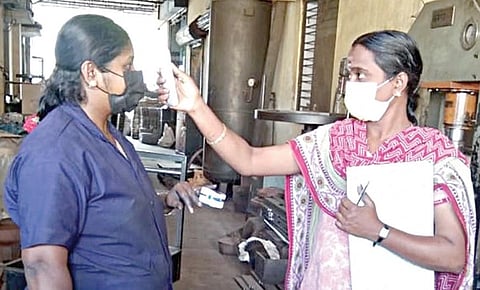 கோவை தொழில் நிறுவனம் ஒன்றில் தொழிலாளரின் உடல்வெப்பத்தை பரிசோதிக்கும் ஊழியர்.