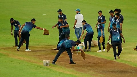 மைதானத்தை உலரச் செய்யும் பணியில் ஊழியர்கள்