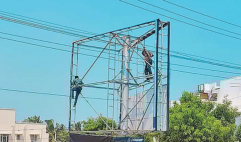 கோவை மாநகராட்சி தெற்கு மண்டலத்துக்கு உட்பட்ட பகுதியில் வைக்கப்பட்டுள்ள விளம்பரப் பலகையை அகற்றும் மாநகராட்சி ஊழியர்கள்.