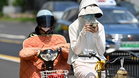 கடந்த மே மாதம் சீனாவின் ஷாங்காய் நகரில் 100 ஆண்டுகளில் இல்லாத அளவுக்கு அதிக வெப்பம் பதிவான நாளில் சாலையில் மக்கள் வெப்ப தற்காப்பு கவசங்களுடன் பயணித்தபோது எடுக்கப்பட்ட புகைப்படம்.