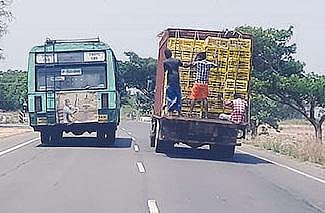 உடுமலை - பொள்ளாச்சி சாலையில் கறிக்கோழி ஏற்றி செல்லும் சரக்கு வாகனத்தின் பின்புறம் ஆபத்தான வகையில் நின்றபடி செல்லும் தொழிலாளர்கள். படம்: எம்.நாகராஜன்