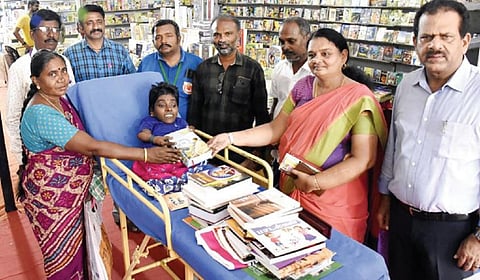 புதுக்கோட்டை புத்தக் திருவிழாவுக்கு நேற்று அழைத்து வரப்பட்ட மாற்றுத்திறனாளி பெண்ணுக்கு புத்தகங்களை வழங்குவோர்.