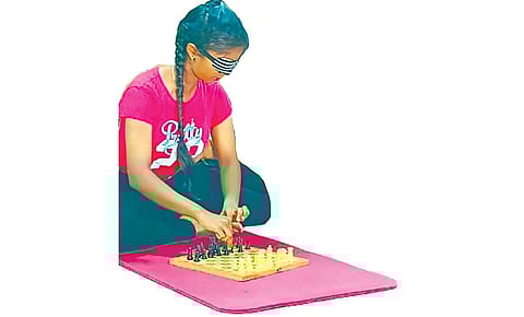 கண்களை கட்டிக்கொண்டு யோகாசனம் செய்தபடி சதுரங்கம் விளையாடும் மாணவி பிரிஷா. படம் : மு.லெட்சுமி அருண்.