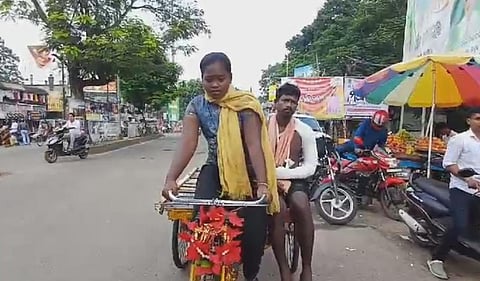 காயம்பட்ட தந்தையை மூன்று சக்கர சைக்கிளில் வைத்து அழைத்துச் செல்லும் சிறுமி