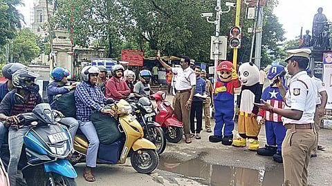 இருசக்கர வாகன ஓட்டுநர், பின்னால் அமர்ந்து பயணித்தவர் என ஹெல்மெட் அணிந்திருந்த இருவருக்கும் கார்ட்டூன் பொம்மைகள் போல் வேடமணிந்த கலைஞர்கள் மூலம் இனிப்பு வழங்கி ஹெல்மெட் அணிவதன் அவசியம் குறித்து போக்குவரத்து போலீஸார் விழிப்புணர்வு மேற்கொண்டனர்.